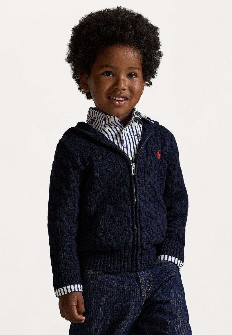 Ναυτικό ζακέτα με πλεχτό σχέδιο και φερμουάρ, με ριγέ πουκαμίσου από κάτω, διαθέτει μπροστινές τσέπες και ριμπ τελείωμα. Ορατές απλές ραφές.