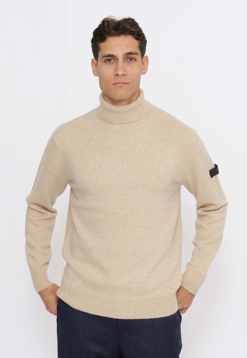 Maglione a collo alto beige realizzato in morbido tessuto a maglia. Presenta polsini e orlo a coste, con una piccola etichetta nera sulla manica sinistra.