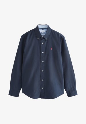 Tumesinine pikkade varrukatega nööbitav särk, valgete nööpide ja väikese punase logoga. Kraega disain ja veidi avarama lõikega. Puuvillane materjal.