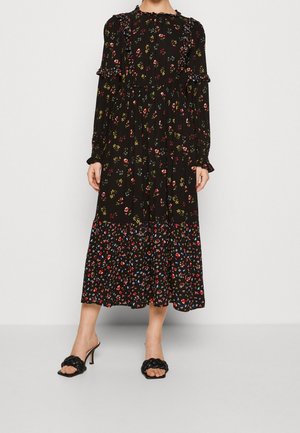 Robe midi noire à manches longues avec imprimé floral multicolore, bordure à volants et ourlet à volants portée avec des sandales à talons hauts noires tressées.