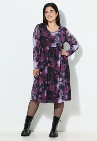 Sukienka z długim rękawem w czarno-fioletowy wzór tie-dye, z plisowan�ą spódnicą i okrągłym dekoltem, w połączeniu z czarnymi butami na sznurowadła.