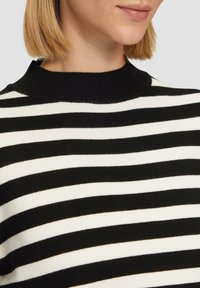 Schwarz-weiß gestreifter Pullover mit hohem Kragen. Der Stoff wirkt weich mit einer glatten Textur und zeigt gleichmäßig verteilte horizontale Streifen.