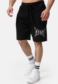 Crne kratke hlače od pamuka s dodatkom elastina, s elastičnim pojasom i velikim bijelim logotipom "TAPOUT". Ima bočne džepove i opušteni kroj, pogodne za ležerno nošenje.
