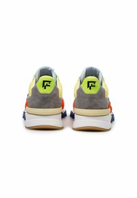 Moniväriset lenkkarit, joissa on sekoitus keltaista, harmaata ja sinistä materiaalia, teksturoitua mokkaa sekä paksu valkoinen pohja oransseilla yksityiskohdilla.