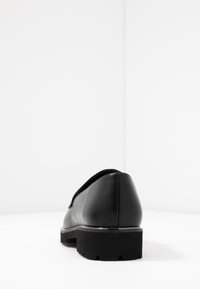 Svart lädersko med rund tå och låg, texturerad gummisula. Minimalistisk design med en slank form och slät yta.