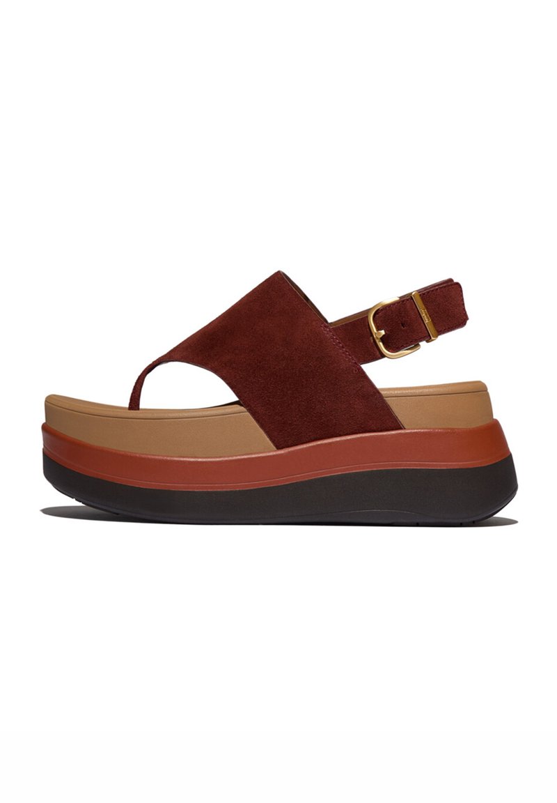 Sandaal met plateauzool met een bovenzijde van bordeauxrood suède, een bruine tussenzool en een zwarte rubberen buitenzool. Voorzien van een verstelbare enkelriem met gouden details.