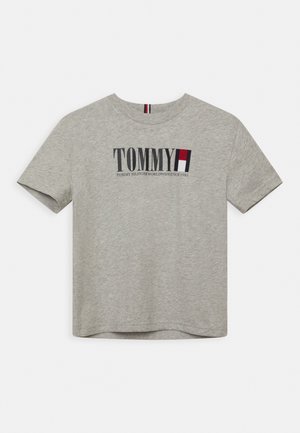 Szara bawełniana koszulka z krótkim rękawem, okrągłym dekoltem i nadrukowanym logo marki w granatowym i czerwonym kolorze. Tekst zawiera "TOMMY" oraz "TOMMY HILFIGER WORLDWIDE 1985."