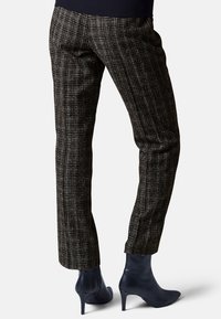 Zwart-wit gestreepte tapered pants met een textuurafwerking, gecombineerd met strakke zwarte enkellaarzen en een gebreide marineblauwe top.