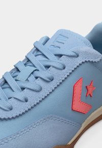 Ανοιχτό μπλε αθλητικό παπούτσι με υφασμένες κορδόνια, σουέντ λεπτομέρειες και κόκκινο αστέρι με λοξό σήμα στη πλευρά.