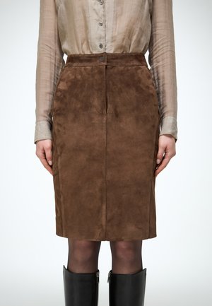 Pruun seemisnahast põlveni ulatuv seelik, mida kantakse läbipaistva beežika nööbitava pluusi ja mustade põlviksaabastega, kujutatud vööst kuni säärteni.