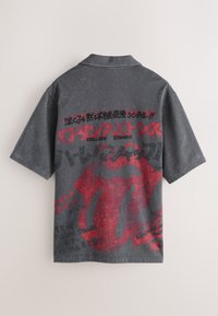 Camicia grigio scuro a maniche corte con il logo rosso della lingua dei Rolling Stones e testo giapponese stampato sul retro.