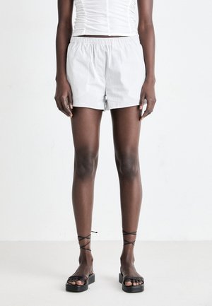 Light gray striped shorts with an elastic waistband. Paired with black strappy flat sandals. Smooth fabric texture, casual fit.