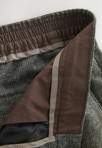 Gray textured fabric with a brown lining. Features a gathered waistband and smooth satin accents along the edges.