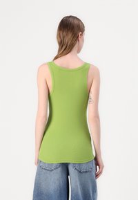Green ribbed tank top with a round neckline and wide armholes. Features a fitted silhouette and soft texture. Back view shown.