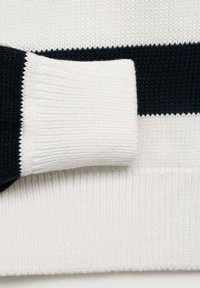 Pletená svetr sleeve v námořnické a bílé pruhy; má vroubkovanou texturu a kontrastní barvy. Měkký materiál s viditelným pleteným vzorem.