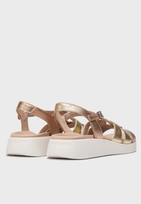 Sandales en cuir rose doré et or métallique avec une semelle plate-forme blanche. Comprend une sangle réglable et un design supérieur texturé.