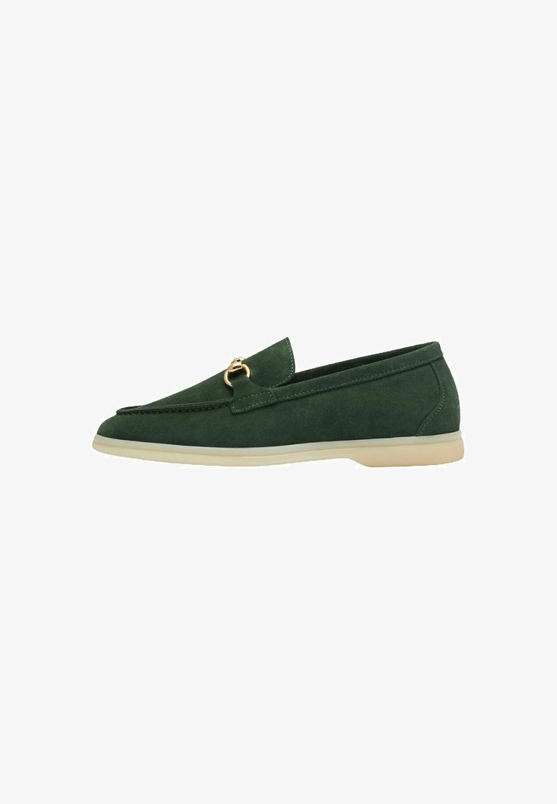 Groene suède loafers met een gouden accent, puntige neus en lage beige zool, voorzien van een gestikt ontwerp langs de rand en een gladde textuur.