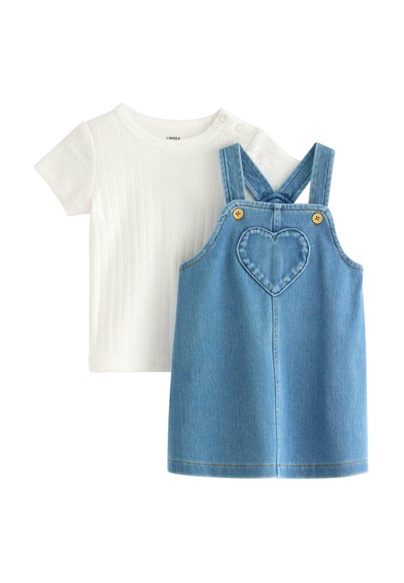 Weißes, geripptes Kurzarmshirt, kombiniert mit einer blauen Denim-Latzhose, die mit einer herzförmigen Tasche und gelben Knöpfen an den Trägern ausgestattet ist.