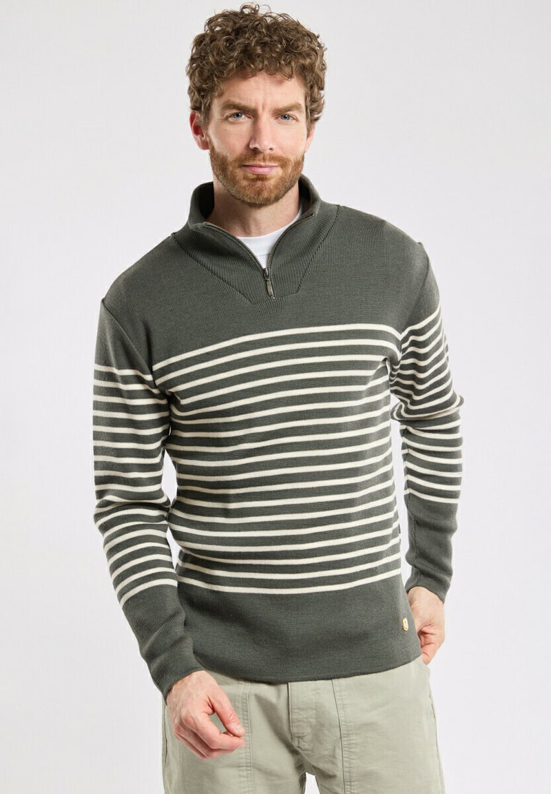 Zielono-kremowy sweter w paski z zapięciem pod szyją. Teksturowany materiał charakteryzuje się długimi rękawami i dopasowanym krojem, podkreślonym logo na dole.