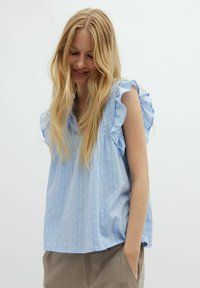 Top senza maniche di colore blu chiaro con spalline arricciate, realizzato in un tessuto testurizzato con righe verticali, caratterizzato da un design a scollo a V e una vestibilità ampia.