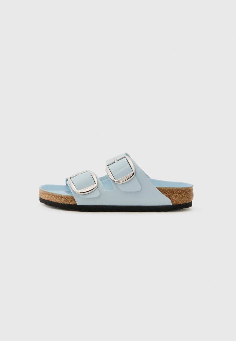 Sandale bleu clair à bout ouvert avec deux boucles argentées réglables, semelle en liège et semelle noire, vue de profil sur un fond neutre.
