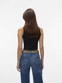 Svart ermeløs topp med høy hals, kombinert med blå vide bukser. Outfiten har et stripete belte med et mønster i gull og svart.