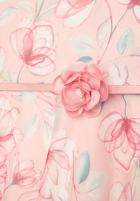 Florales Kleid aus leicht rosa Stoff mit großen Blumenmustern in Pink- und Grüntönen. Akzentuiert mit einem Detail einer rosa Stoffrose.