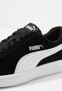 Black Puma sneaker with white side stripe, black laces, and visible Puma logos on tongue, side, and sole.