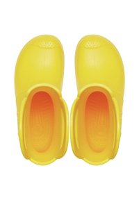 Sabots en caoutchouc jaunes avec un bout arrondi, design à enfiler et semelle texturée. L'intérieur présente un dégradé orange.