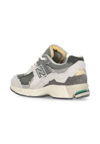 Scarpa da atletica grigia e bianca con un mix di materiali scamosciati e in rete, suola ammortizzata e suola esterna in gomma texturizzata. Dettagli del logo ben visibili.