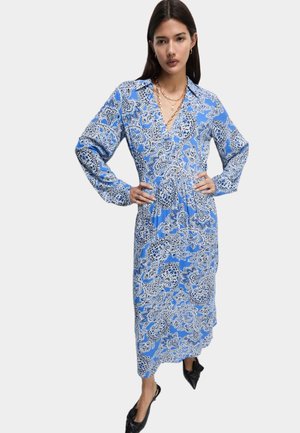 Blå mønstret kjole med V-hals, lange ærmer og en løs pasform. Stoffet har et blomstret og paisley-design i hvid.
