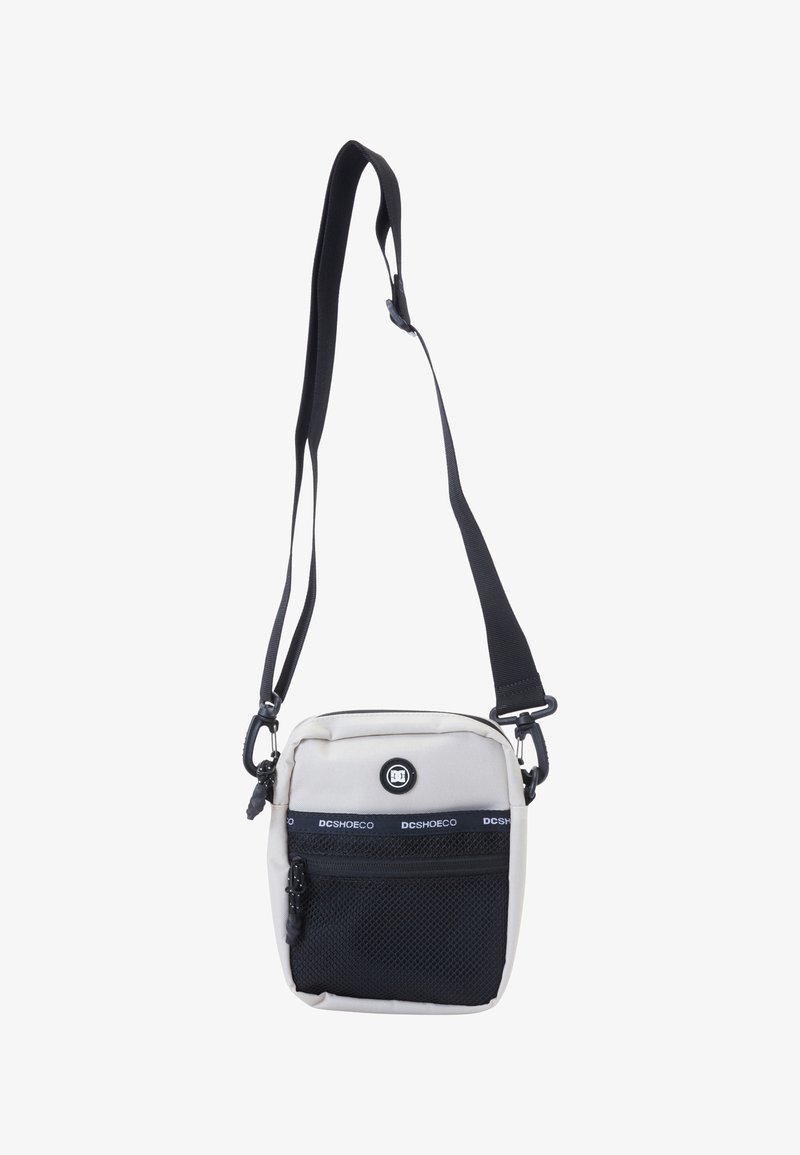Malá čtvercová crossbody taška vyrobená z světle šedé látky s černou síťovanou přední kapsou. Obsahuje nastavitelný popruh a detail s logem.