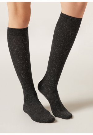 Calzini neri al ginocchio con finitura testurizzata, caratterizzati da sottili screziature di colore e un polsino a costine in cima. Materiale morbido ed elastico.
