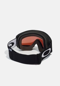 Skibril met een zwart-wit elastische band, voorzien van een drie-laags schuimvoering en getinte oranje lens voor verminderde schittering.