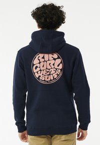 Marine hoodie met een grote roze ronde grafiek op de achterkant, met "RIP CURL WETSUITS" in vette, ronde tekst. Zacht materiaal, ontspannen pasvorm.