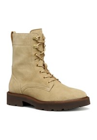 Stivale beige in suede al polpaccio con hardware dorato, punta rotonda e suola in gomma marrone. Presenta lacci e una superficie testurizzata.