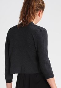 Mörkgrå kort cardigan med trekvartslånga ärmar, tillverkad av mjukt material, med en slät textur och sömlös axeldesign.