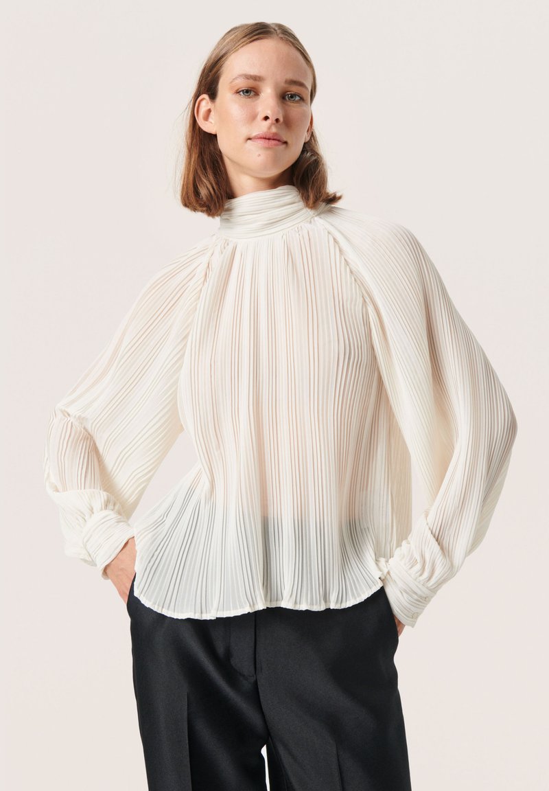 Witte geplooide blouse met een hoge hals, luchtige mouwen en elastische manchetten. De stof heeft een gladde textuur met verticale strepen.
