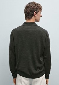 Mörkgrå tröja med krage, långa ärmar och ribbad nederkant. Mjuk textur, enfaldig design, sedd bakifrån.