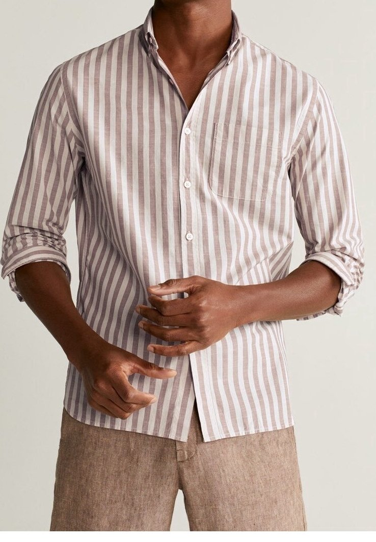 Camisa de botones hecha de tela ligera con rayas verticales en tonos rosa apagado y blanco, con un bolsillo en el pecho y mangas remangadas.