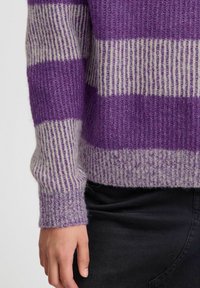 Adīts purpura un gaiši pelēks svītrains džemperis ar teksturētu apdari, ar ribinātām piedurknēm un brīvu piegriezumu.