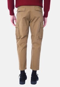 Pantaloni cargo in khaki con due tasche laterali, taglio dritto e lunghezza cropped. Realizzati in resistente tessuto di cotone, presentano una vita piatta.