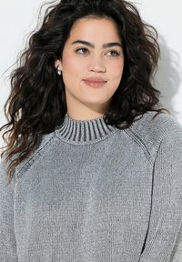 Maglione grigio a maglia con collo alto e dettagli a coste, maniche raglan, che mette in mostra un pattern di tessuto testurizzato.