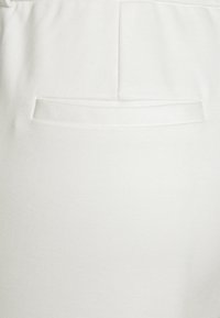 Witte katoen broek met een discrete achterzak met een paspelontwerp. De stof heeft een soepele structuur en minimaal zichtbare naden.