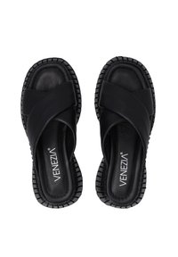 Černé sandály na slip-on s překříženými pásky, vyrobené z měkkého materiálu. Texturovaná gumová podrážka s drážkami pro lepší přilnavost. Viditelné jméno značky "VENEZIA".