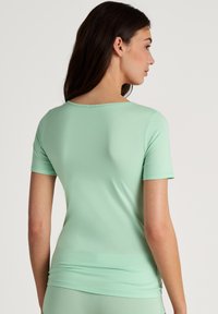 Mintgroene top met korte mouwen, gemaakt van zachte, rekbare stof. Heeft een ronde halslijn en een aansluitende pasvorm.