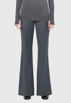 Person wearing dark gray flared pants, a matching long-sleeve sweater with thumb holes, and black shoes against a plain background.