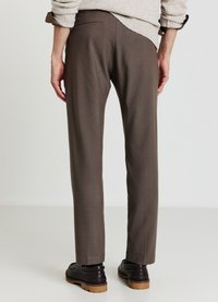 Pantaloni marroni su misura con una texture liscia, caratterizzati da una vestibilità slim, tasca posteriore discreta e una finitura pulita. Abbinati a scarpe scure.