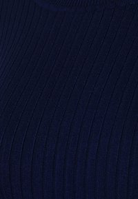 Gros plan sur un tissu bleu marine avec une texture côtelée verticale en tricot.