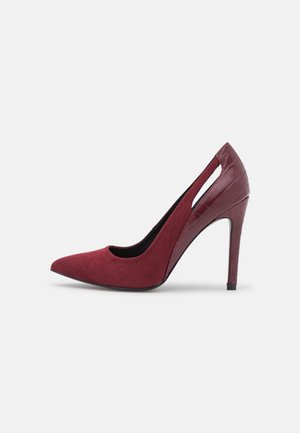 Escarpin bordeaux à talon haut avec bout pointu, côtés découpés et texture crocodile sur le talon et la tige arrière.